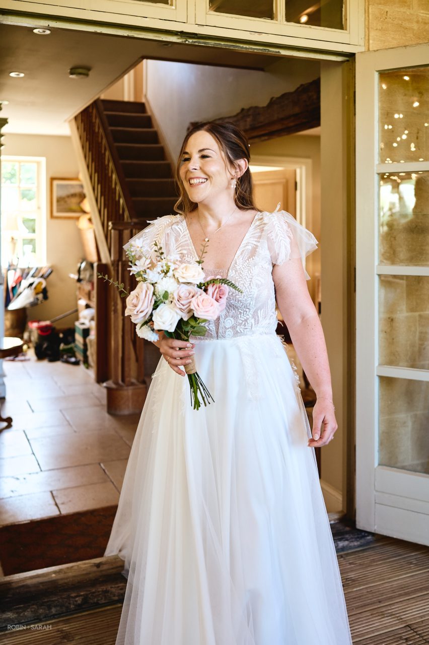 Bride walks through Charingworth House and greets her dad who is waiting to see her in her dress