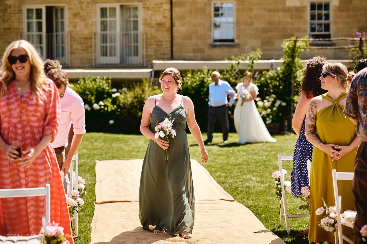 Bridesmaid walks up aisle during outdoor wedding ceremony