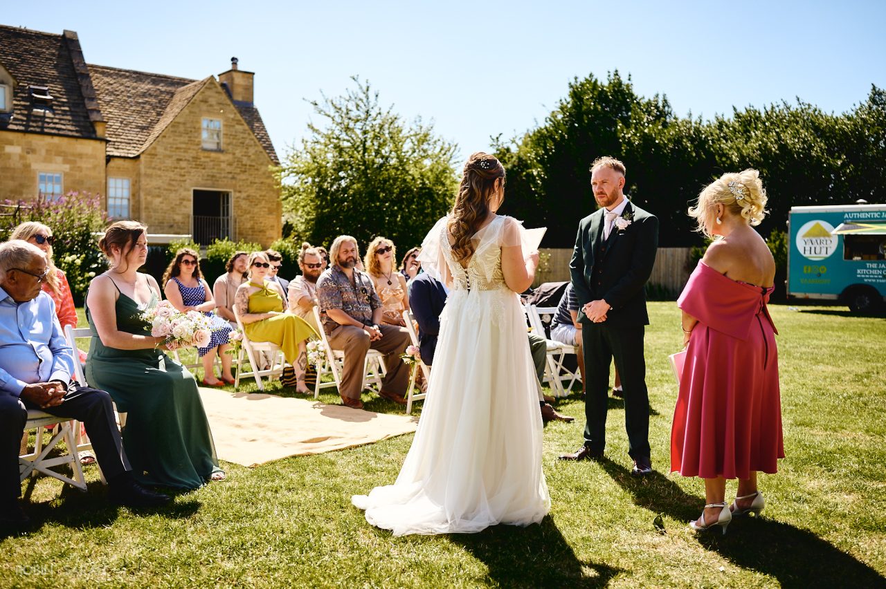 Bride and groom read vows during outdoor wedding ceremony at Charingworth House