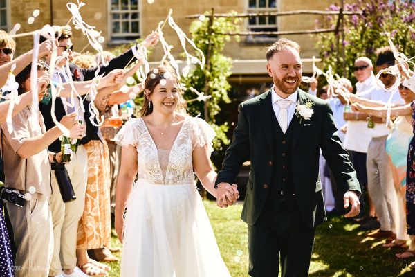 Bride and groom walking through guests as they wave ribbon wands and blow bubbles