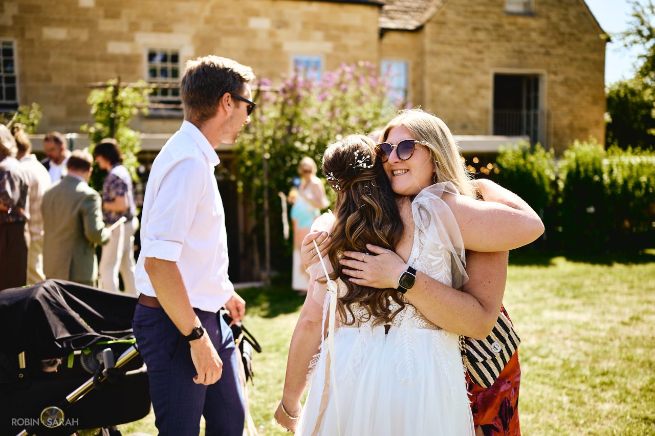 Bride hugged by wedding guest after ceremony at Charingworth House