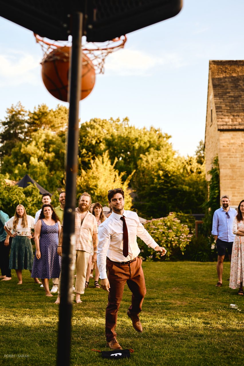 Wedding guests shoot basketball hoops during evening reception at Charingworth House