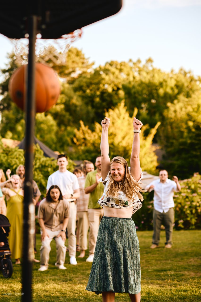 Wedding guests shooting basketball hoops during evening wedding reception at Charingworth House
