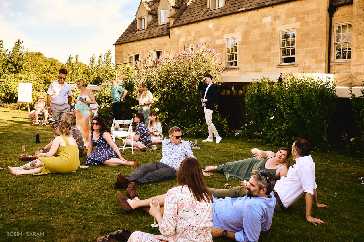 Wedding guests chat and relax in the grounds Charingworth House