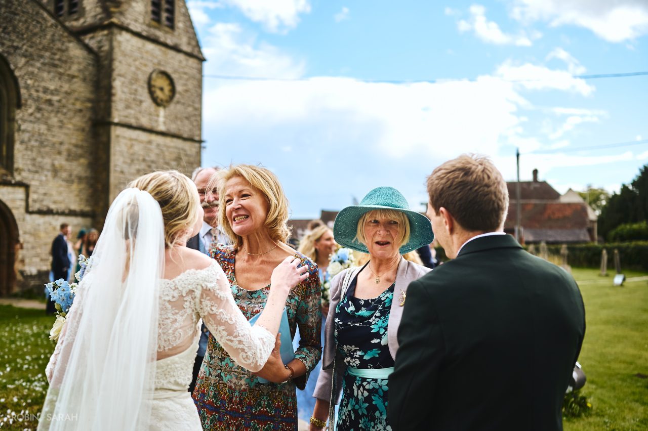 Wedding guests congratulate couple in churchyard at St Peter's church Bourton-on-Dunsmore