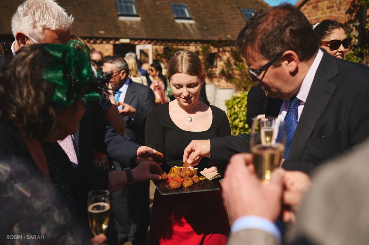 Wedding guests take nibbles from tray during drinks reception at Wethele Manor