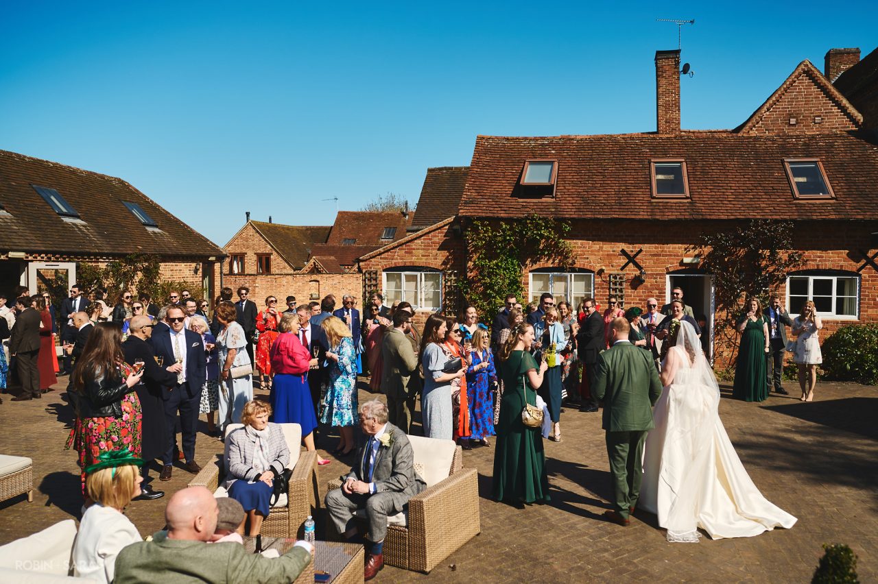 Bride and groom chat to wedding guests in courtyard at Wethele Manor during drinks reception