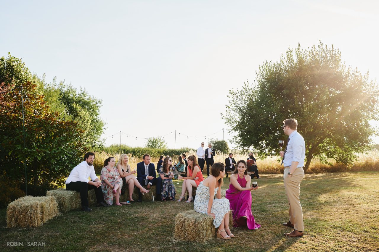 Wedding guests chat and relax in the evening light outside the marquee at Wethele Manor