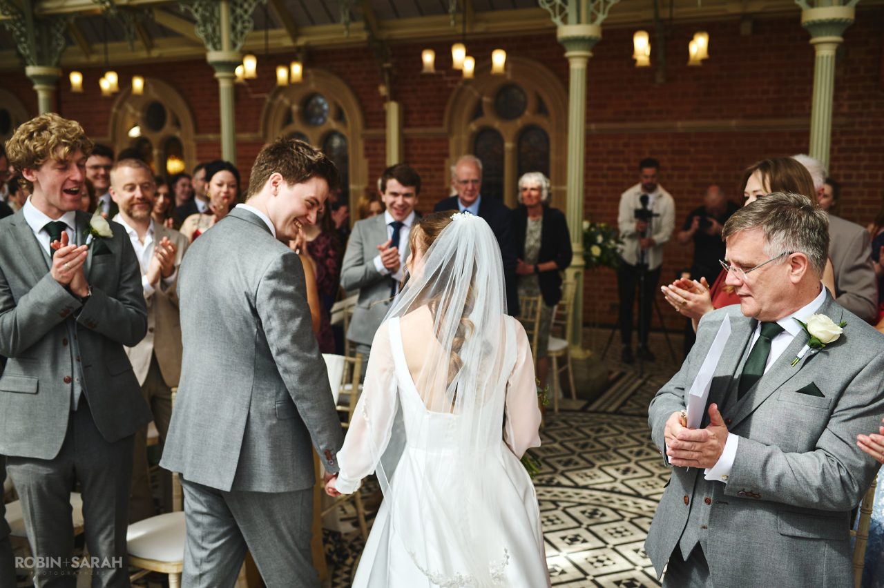 Guests clap as bride and groom leave wedding ceremony in The Orangery at Kilworth House