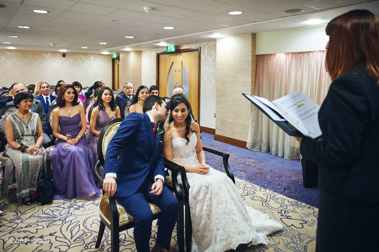 Groom whispers in bride's ear during wedding ceremony at Solihull Register Office