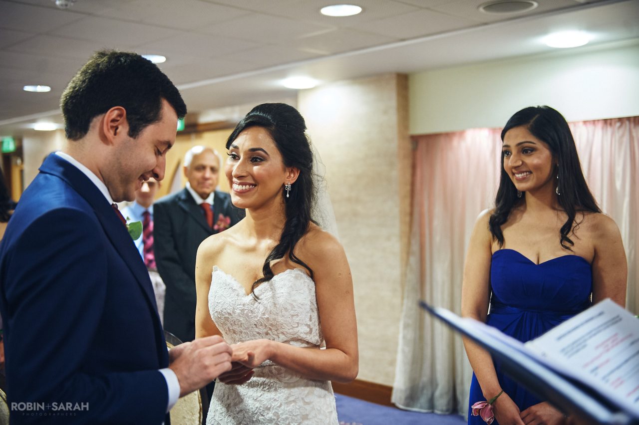 Groom places wedding ring on bride's finger
