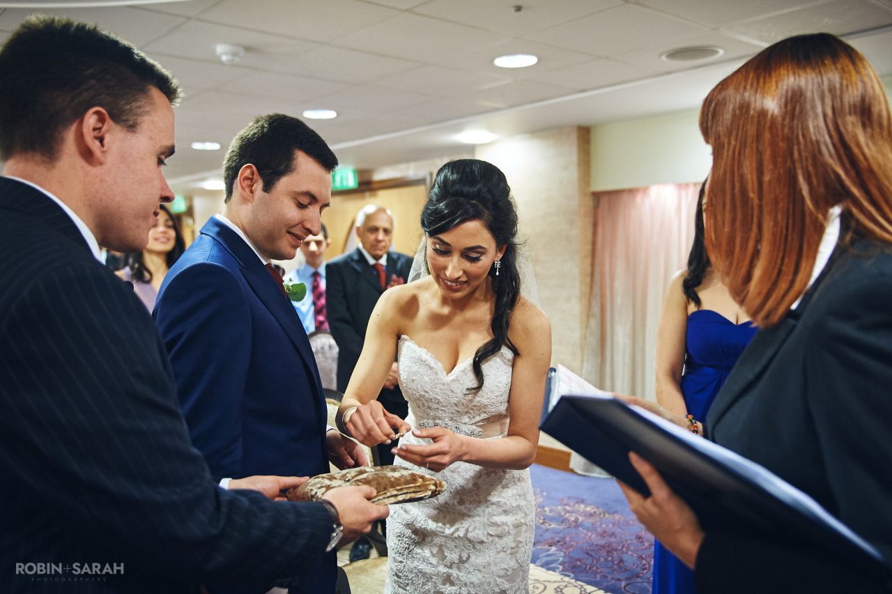 Bride lifts wedding ring off decorative cushion at Solihull Register Office