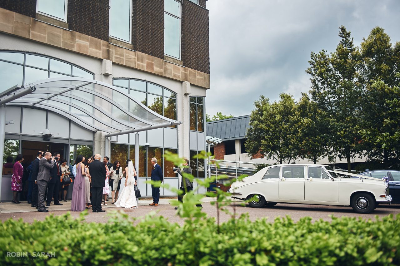 Wedding guests gather around bride and groom outside Solihull Register Office after marriage ceremony